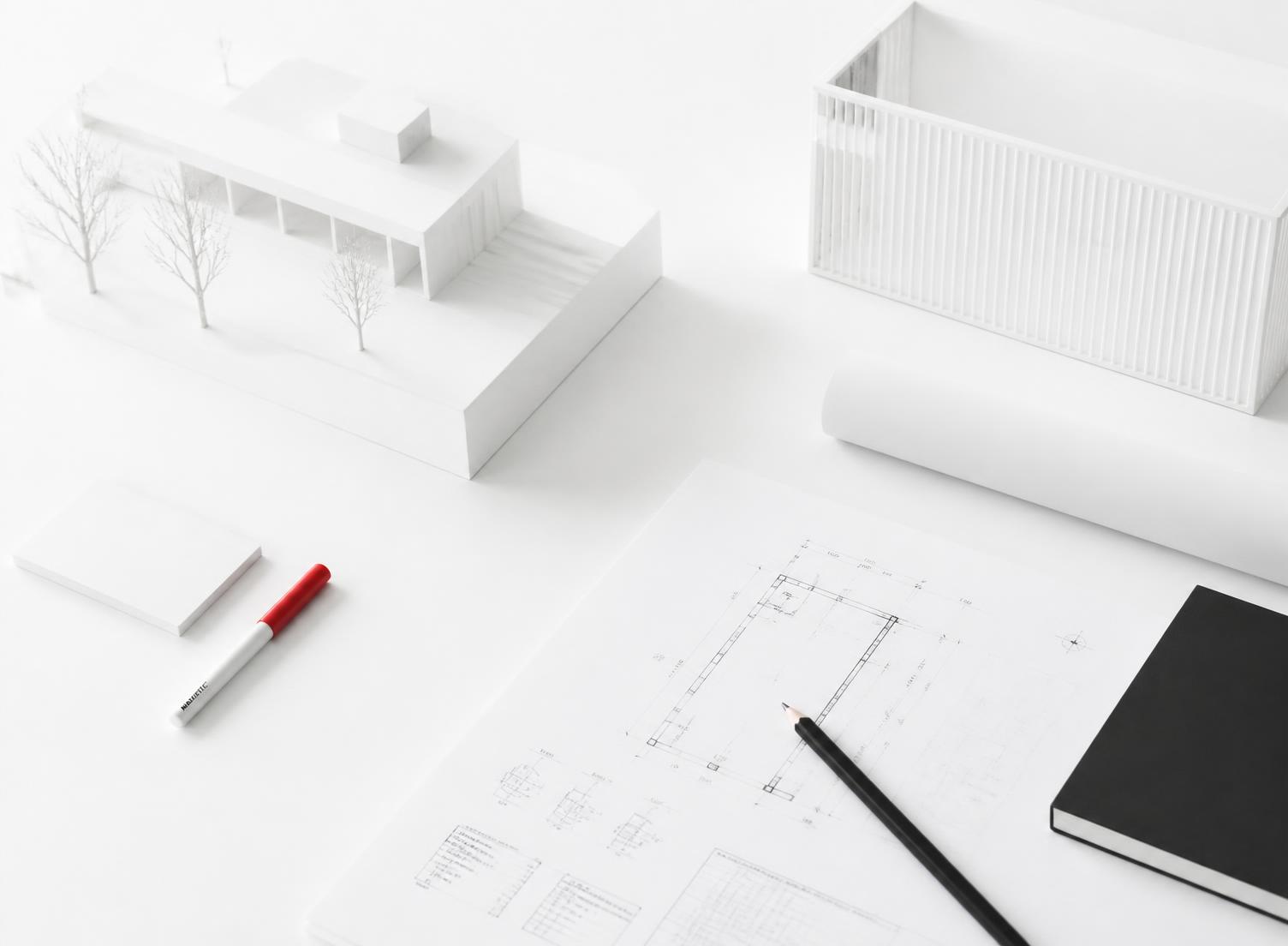 Tavolo da lavoro con disegni tecnici, modelli in scala e campioni di materiale